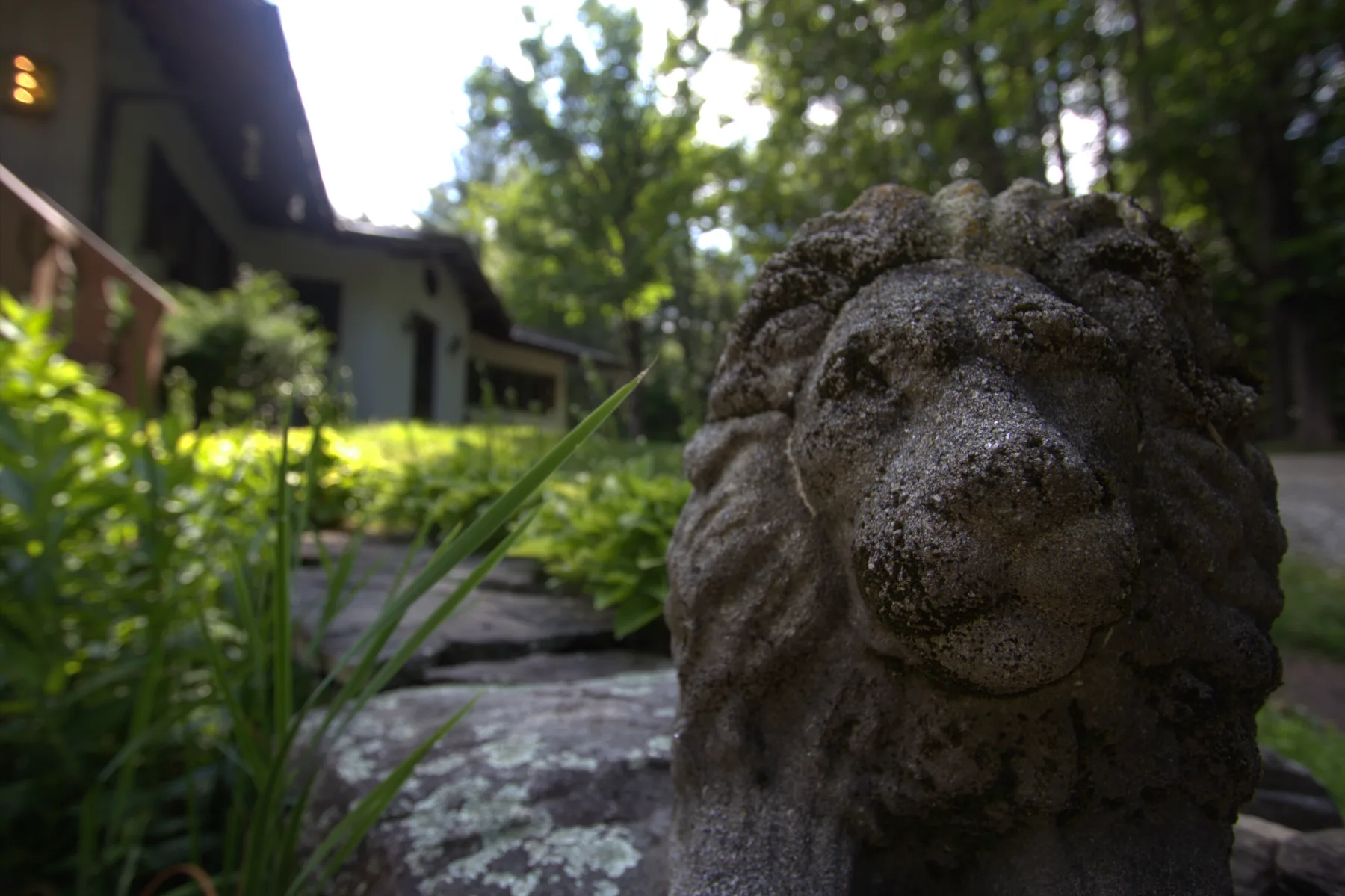 A stone lion at the garden steps, the chalet beyond