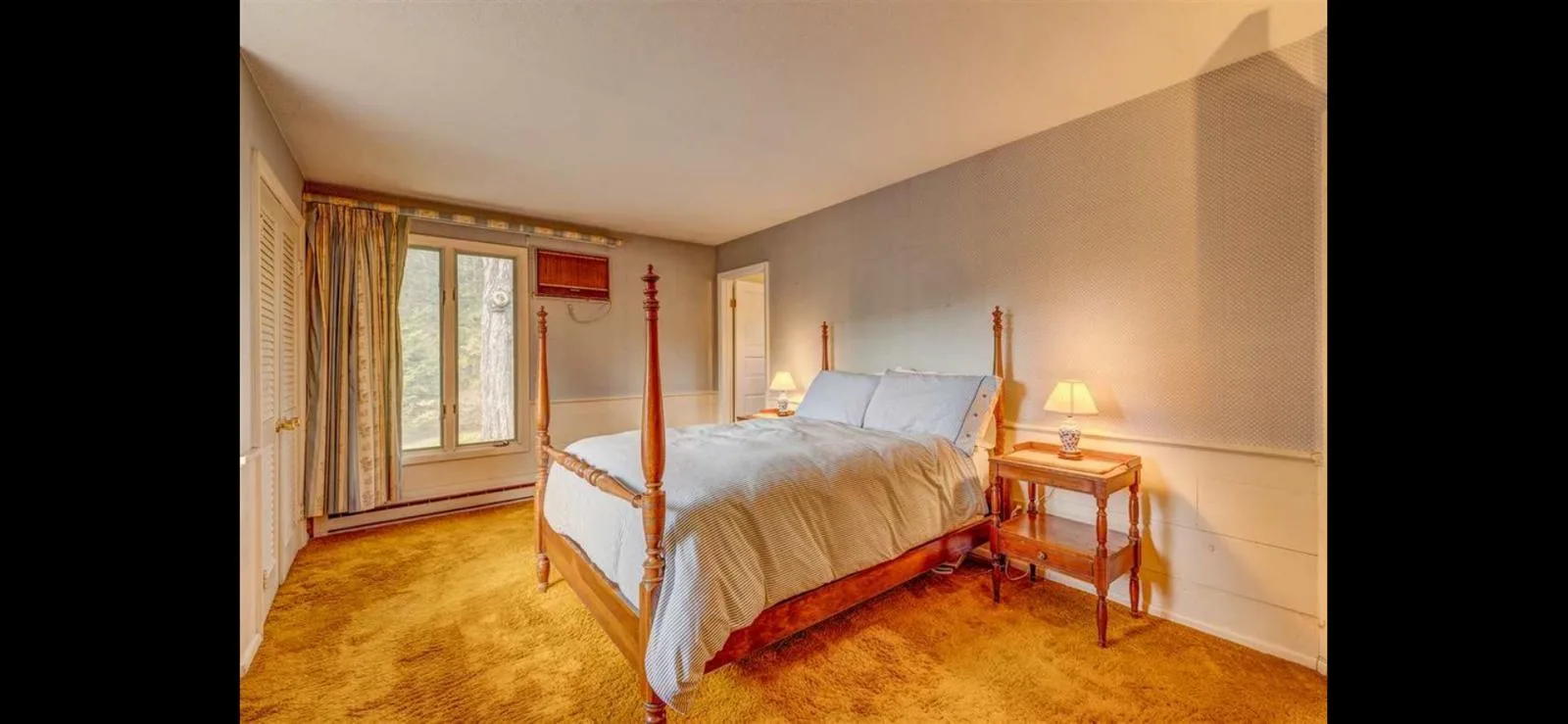 A bedroom with a four-poster bed and forest views
