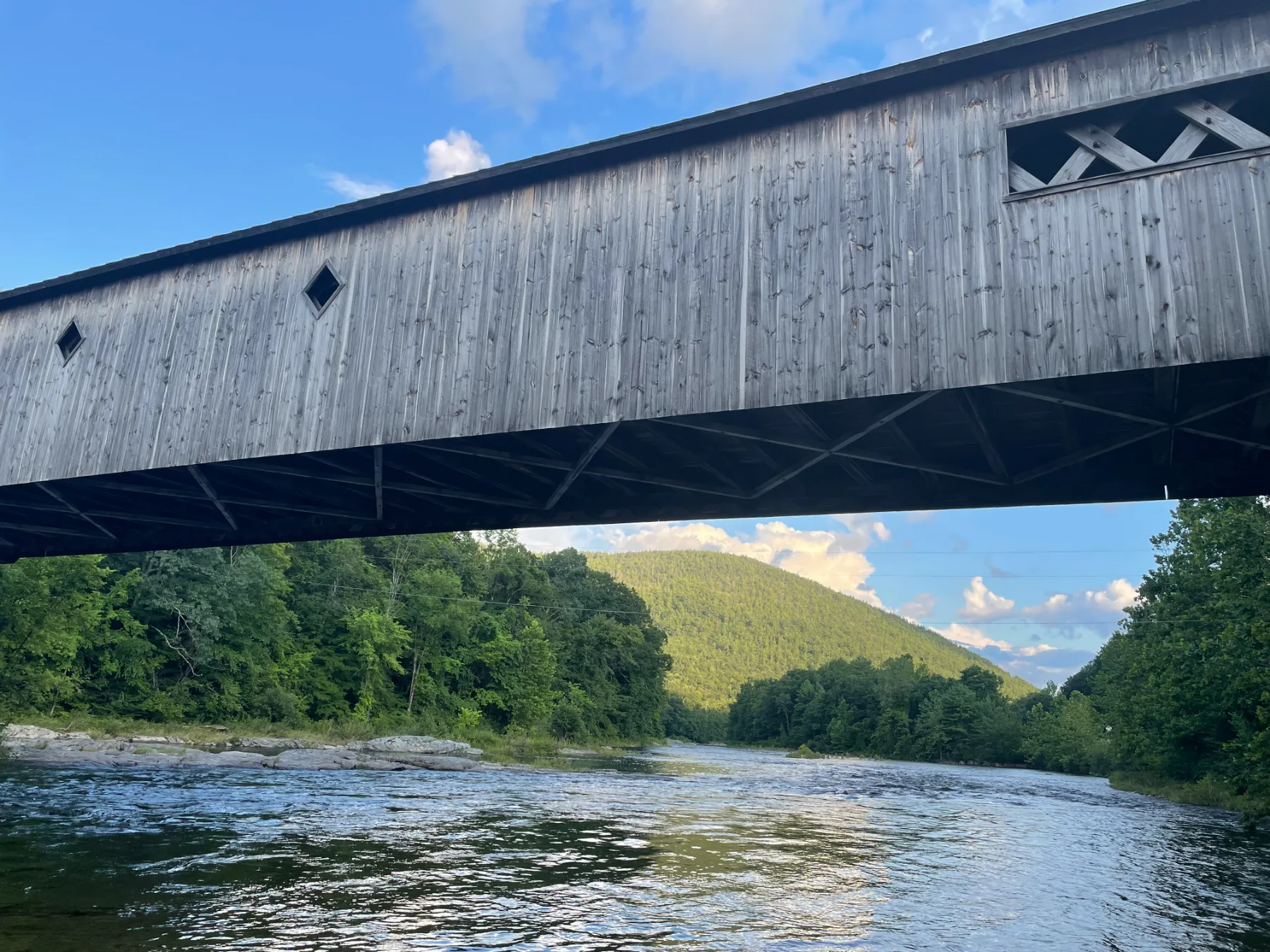A covered bridge over the river beneath the mountains